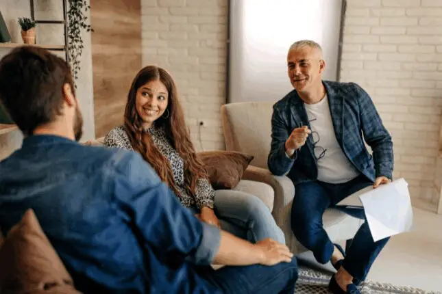 Two men and a woman sit in a therapy office having a lively conversation