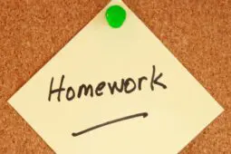 A yellow post-it with the word "homework" written on it is pinned to a cork board