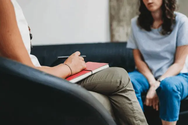 A therapist and client sit across from each other in the therapy room