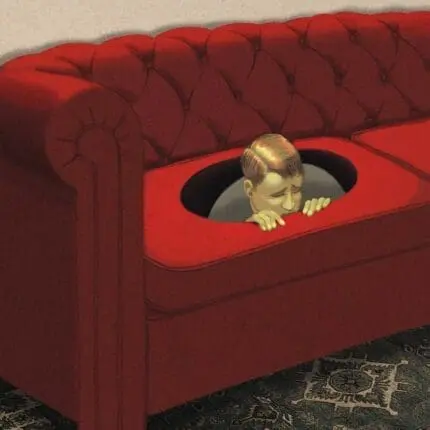 A young boy hides in a hole in a couch