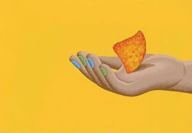 A hand holds a tortilla chip