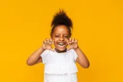 A young girl holds her hands up playfully