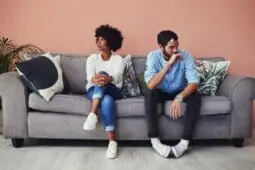 A couple on a couch faces away from each other