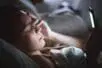 A woman awake in bed looks at her phone