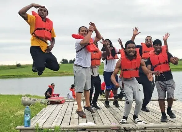 A group of kids in life vests play on a dock