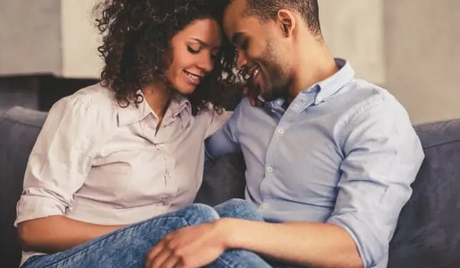 A man and a woman cuddling on a couch