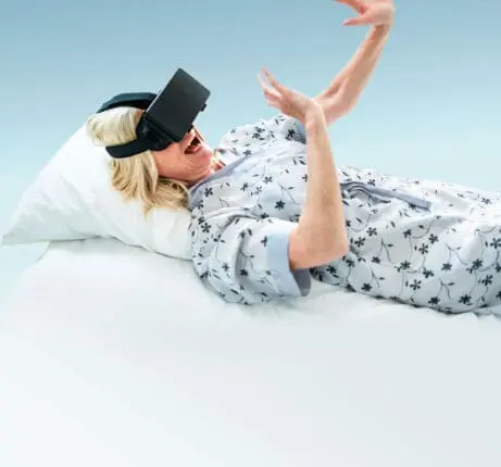 A woman lying in bed with a VR headset on