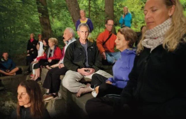 A man sits cross-legged amongst a crowd