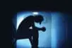 A teenager looks at the floor with his elbows on his knees
