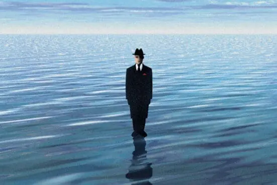 A man in a suit stands in a body of water