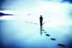 A figure walking on a path of stones through water and reaches as fork