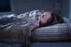 A young girl hides under her covers