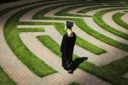 A woman in academic regalia walks a labyrinth