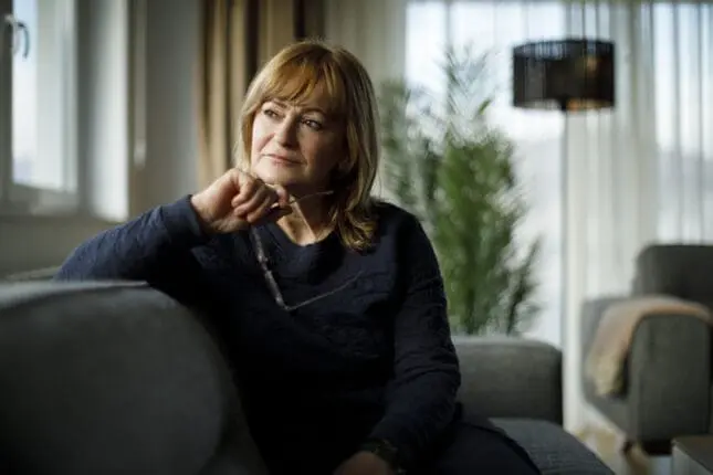 A woman sits on couch contemplating and looking into the distance