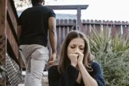 Woman on the stairs looking sad as man walks away behind her | Photo by Rodnae-Productions/Pexels