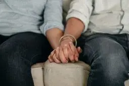 Two people holding hands on a couch | Photo by Ketut Subiyanto/Pexels