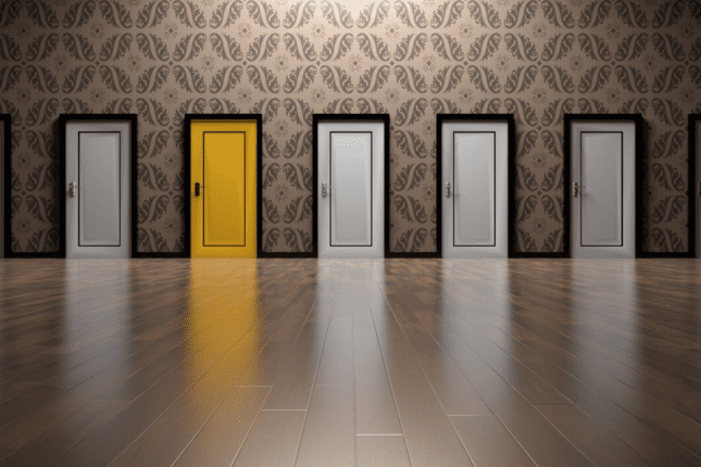 A rows of doors side by side, all in white except for one that is bright yellow