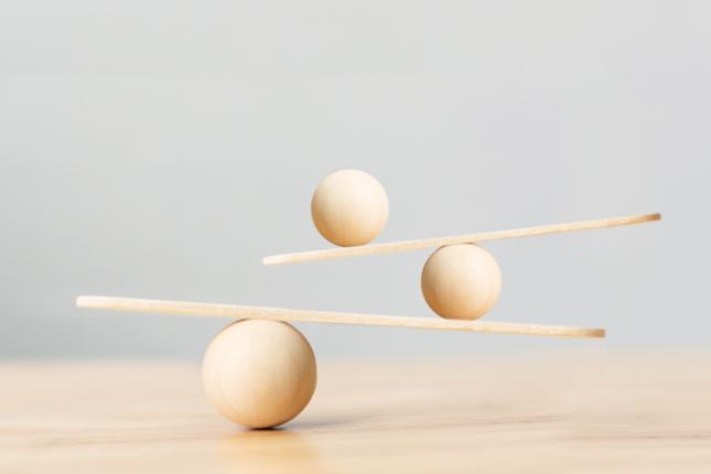 Three wooden balls balancing on wooden boards on a table.