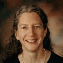 Woman smiling against a dark background.