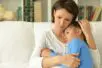 Image of a mother holding her upset daughter as they sit on a couch