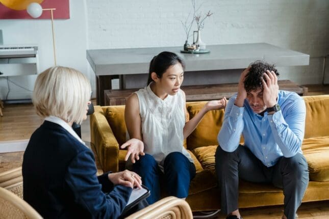 A couple arguing on a couch with a therapist watching | Photo by Timur Weber/Pexels